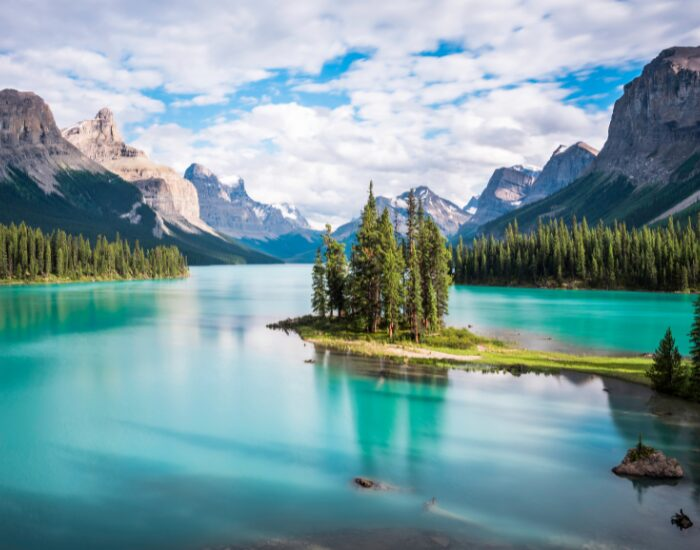 spiritislandinmalignelakeatsunsetjaspernationalparkalbertacanada.webp panoramic view of jasper national park with green lakes and mountains in the background