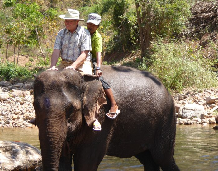 Two tourists mounting an asian elephant in thailand