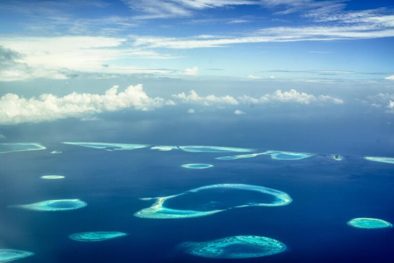 A stunning aerial view of a tropical archipelago with clear blue waters and scattered islands under a bright sky.