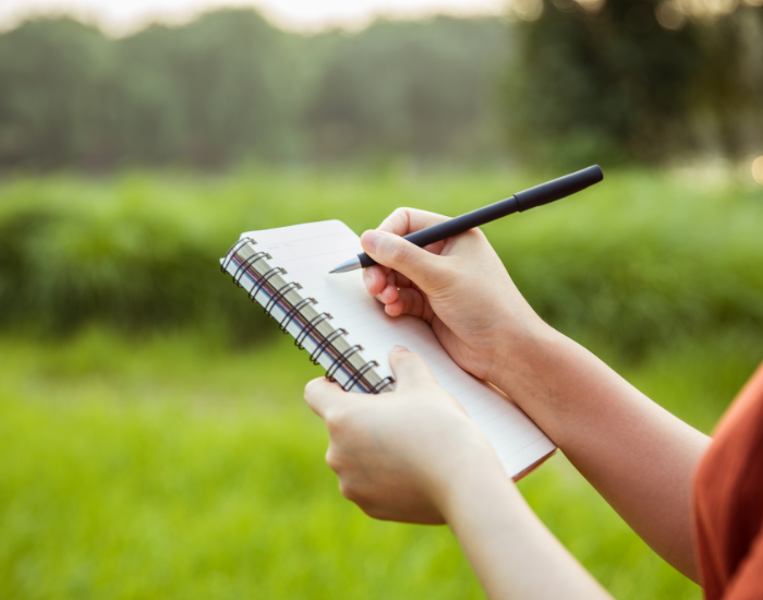 writting nature hand holding a pen writting in a notebook in nature