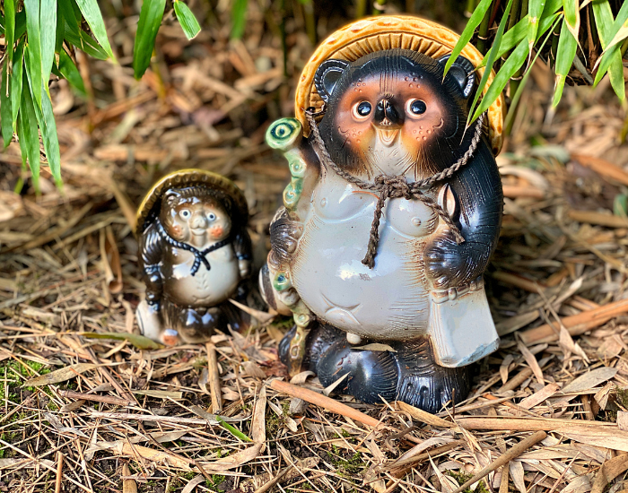 Tanuki.webp two tanuki statues standing over the ground