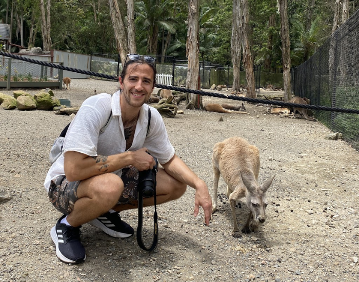 a man sitting next to a kangaroo in an enclosure