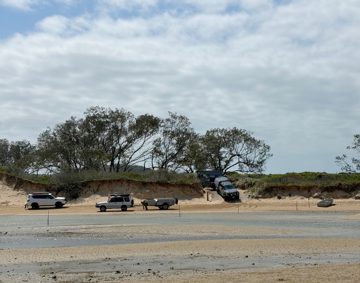 view of a beach water crossing at low tide with trucks lining up
