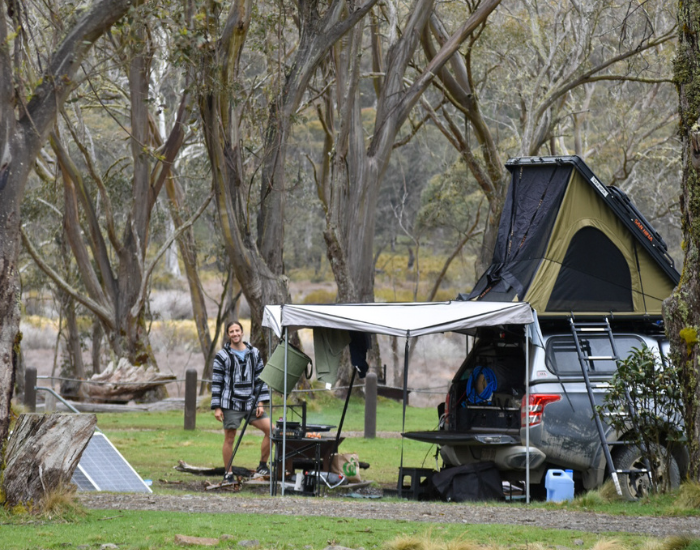 a man standing next to a car with a rooftent and an awning